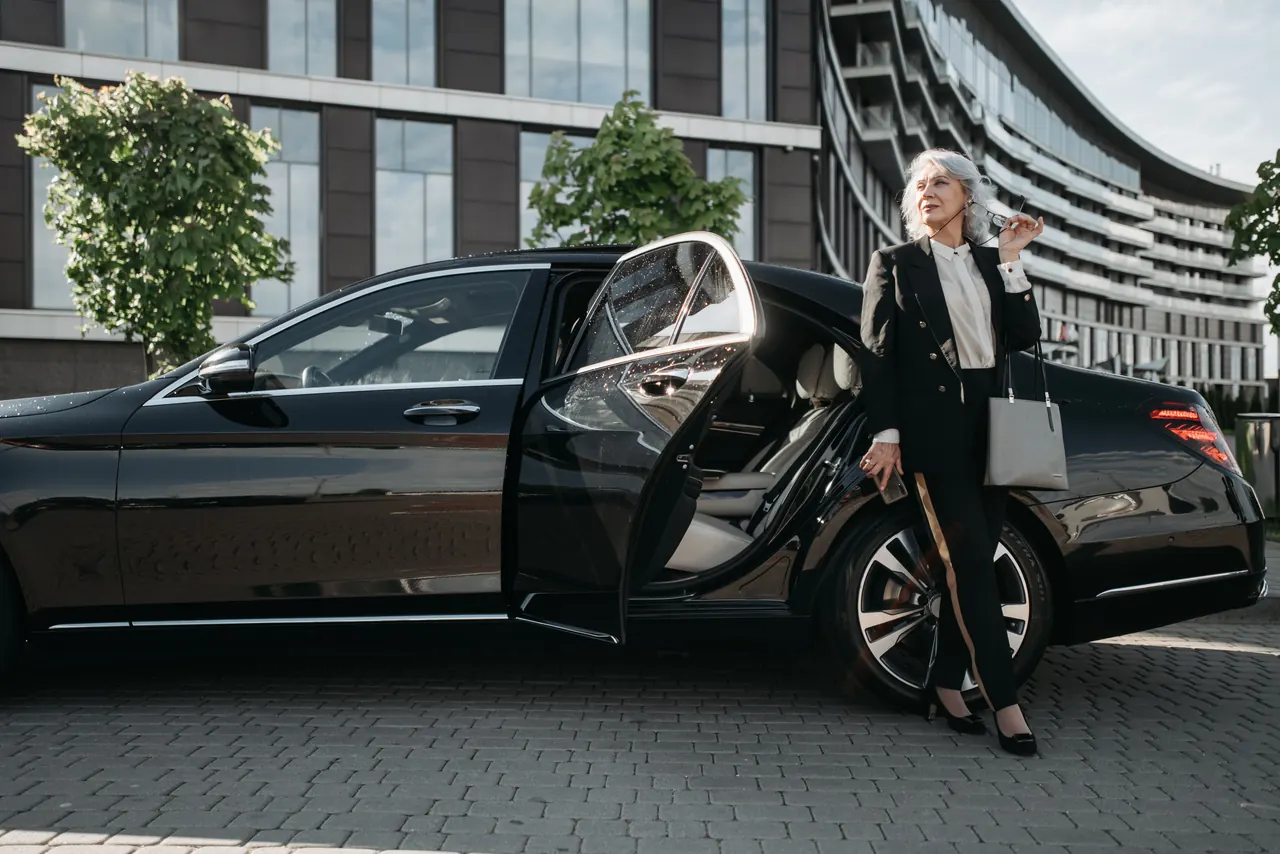 An executive stepping out of a black Mercedes S-Class